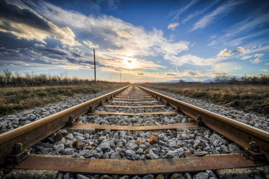 railroad track extending to the horizon under a blue sky with clouds