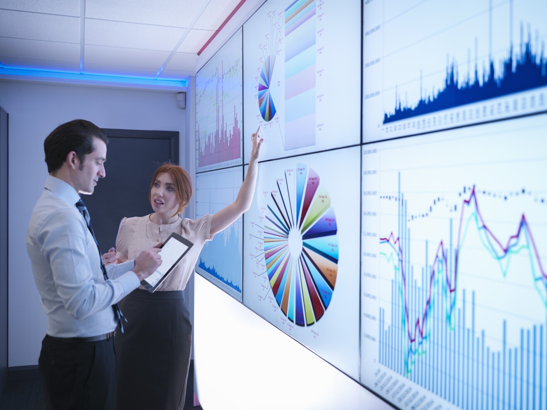 Business colleagues discussing graphs on screen in meeting room