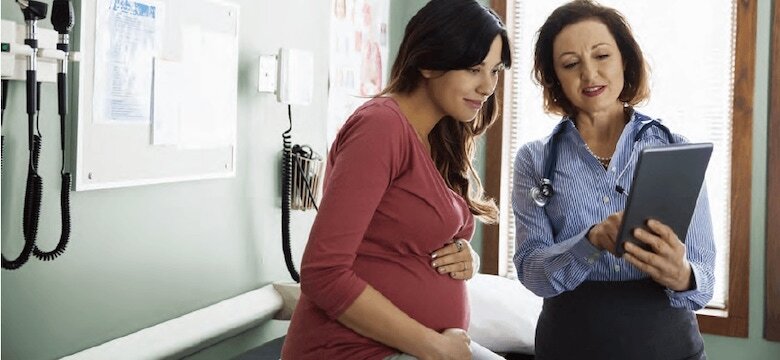 doctor reviewing information on a tablet with pregnant patient