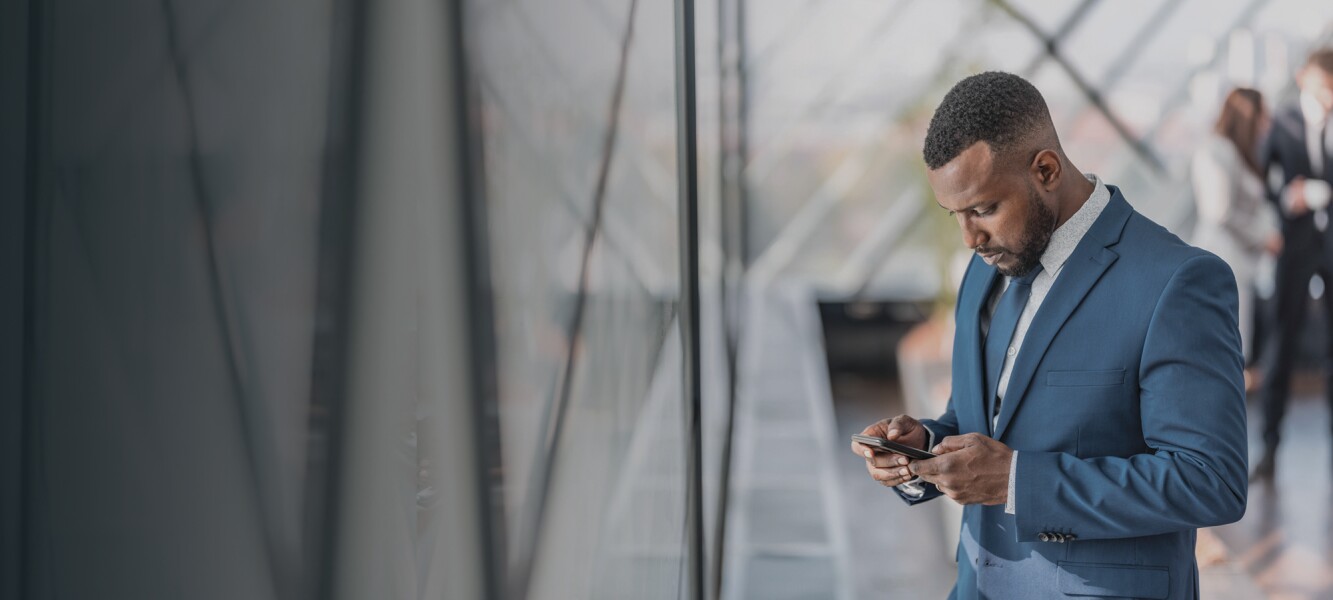 Businessperson standing by the window looking at his mobile phone