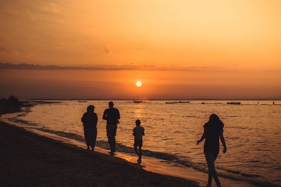 family walking along the shoreline in Rhode Island at sunset