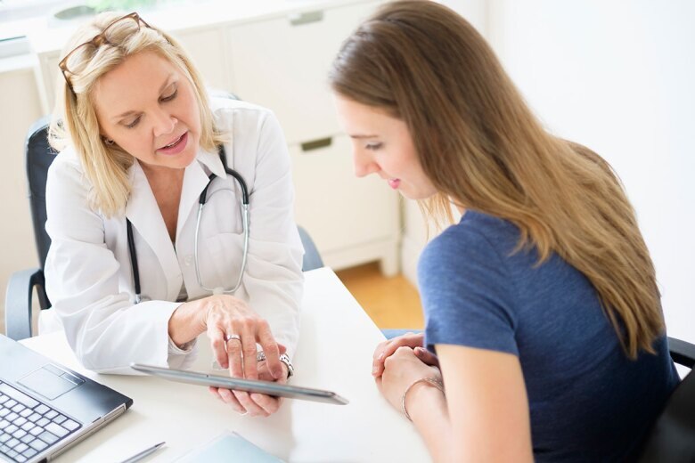 female doctor reviewing patient record with young woman