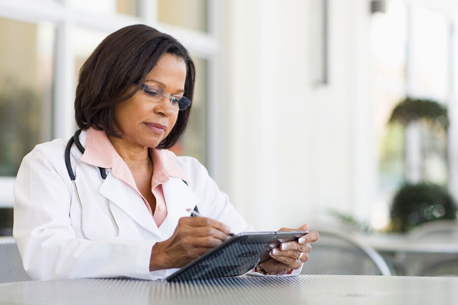 Female doctor reviewing research on her tablet while working