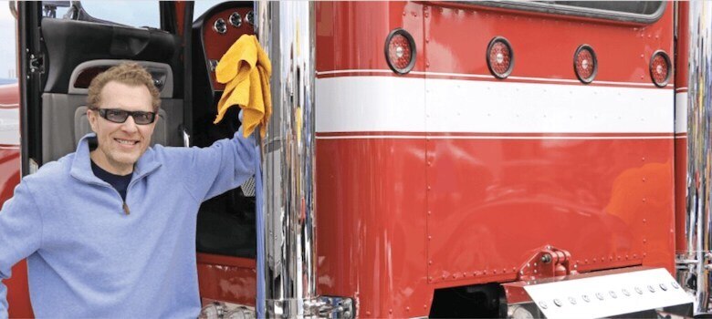 man standing outside the open cab of a semitruck