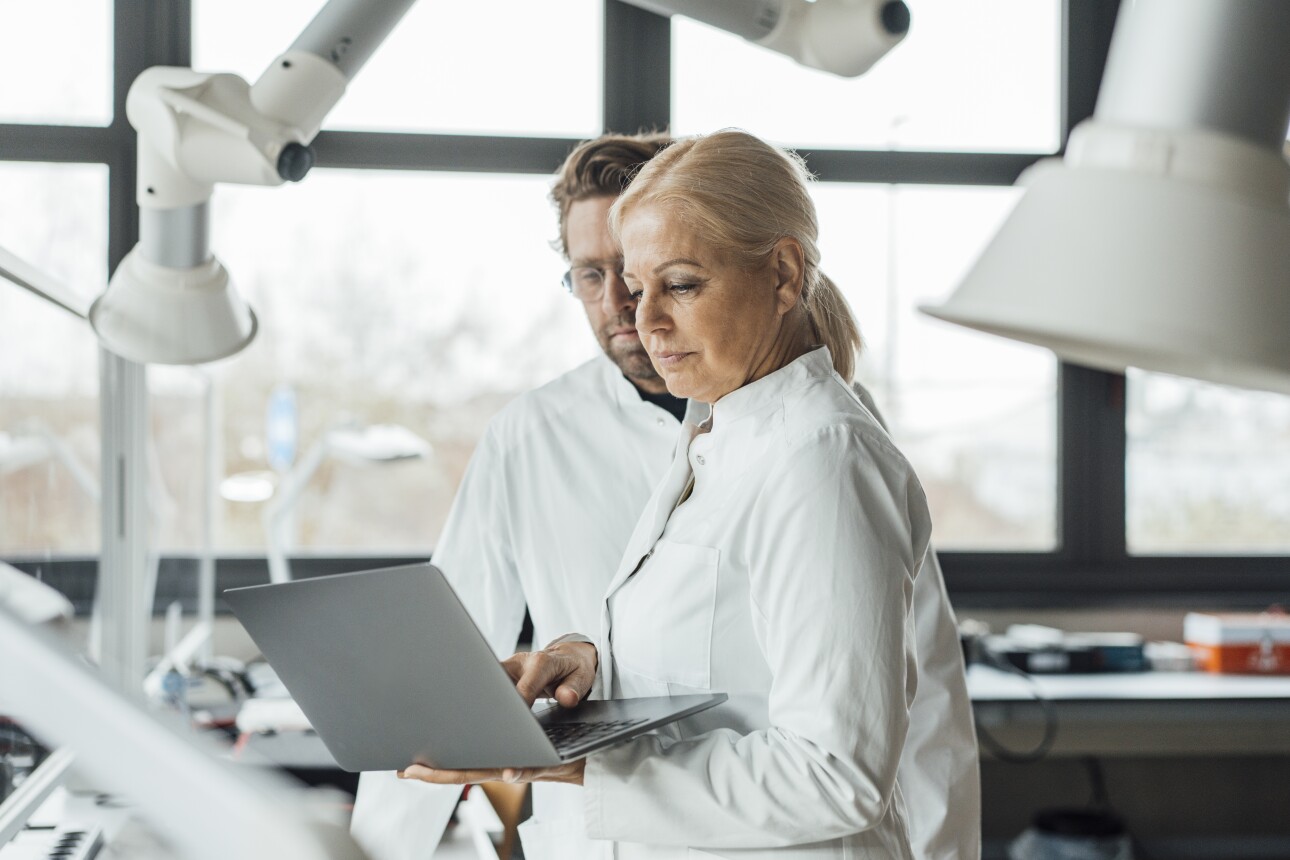 Mature scientist with colleague using laptop