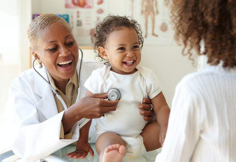 doctor listening to the heart of a smiling toddler patient