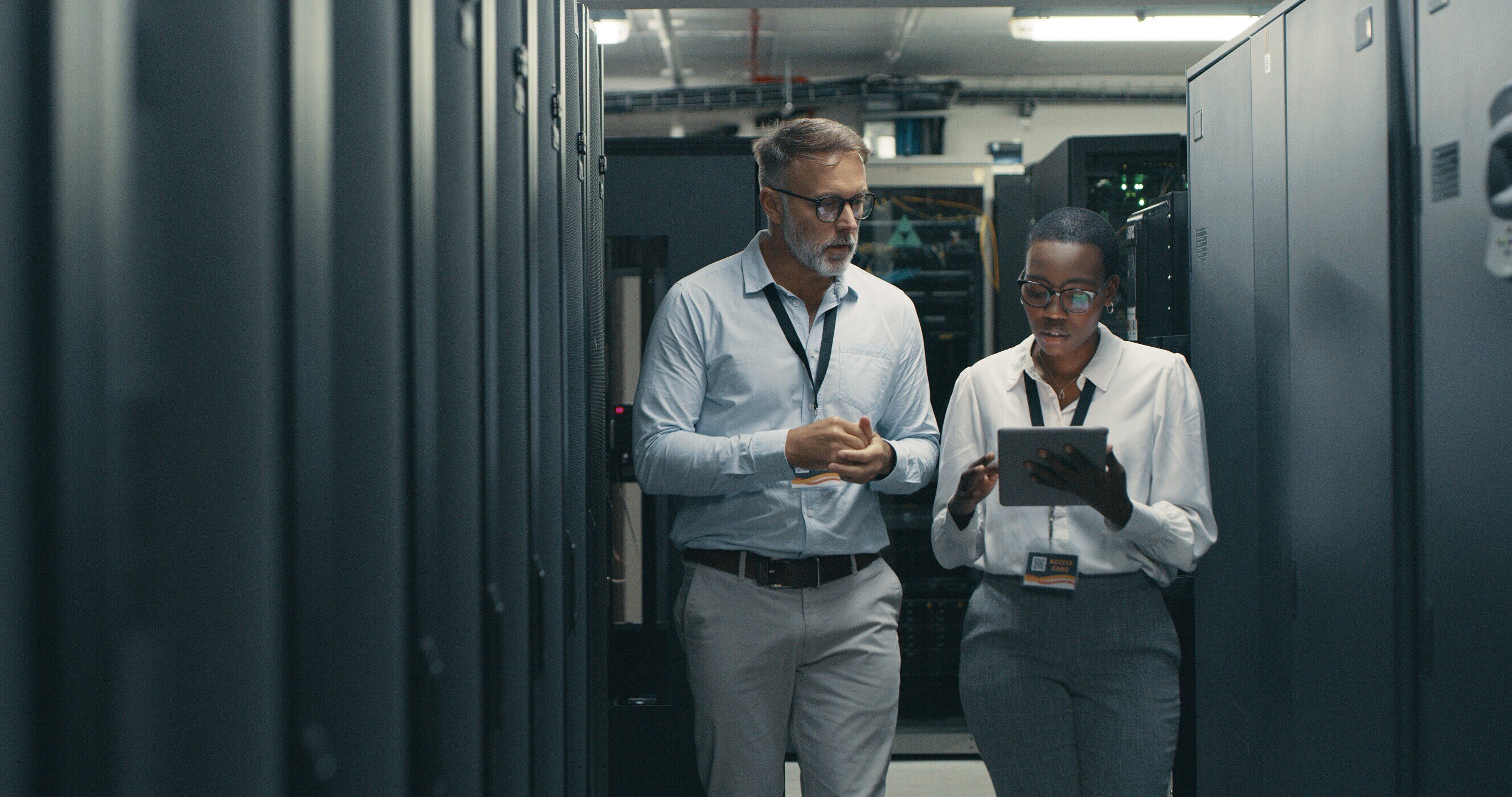 man and woman using a digital tablet while working in a data centre