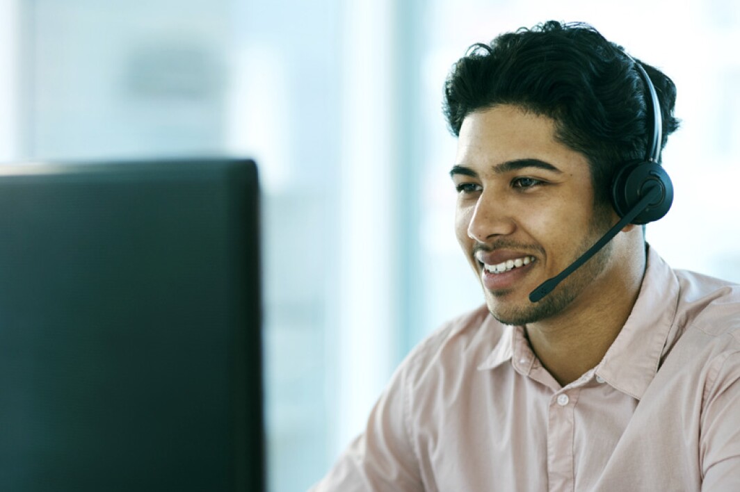 customer support representative wearing a headset and looking at computer screen
