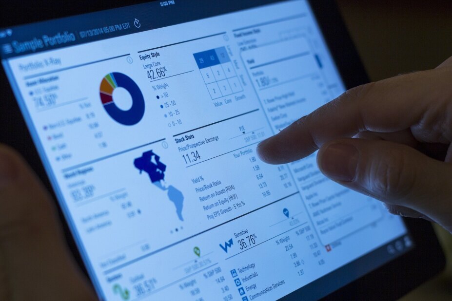 Employee of a capital market firm reviewing the portfolio of a client on a tablet