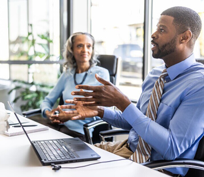 Young businessman speaking to colleagues in modern conference room