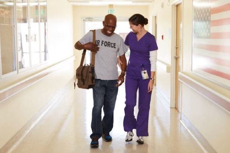 nurse walking with veteran patient in hospital hallway